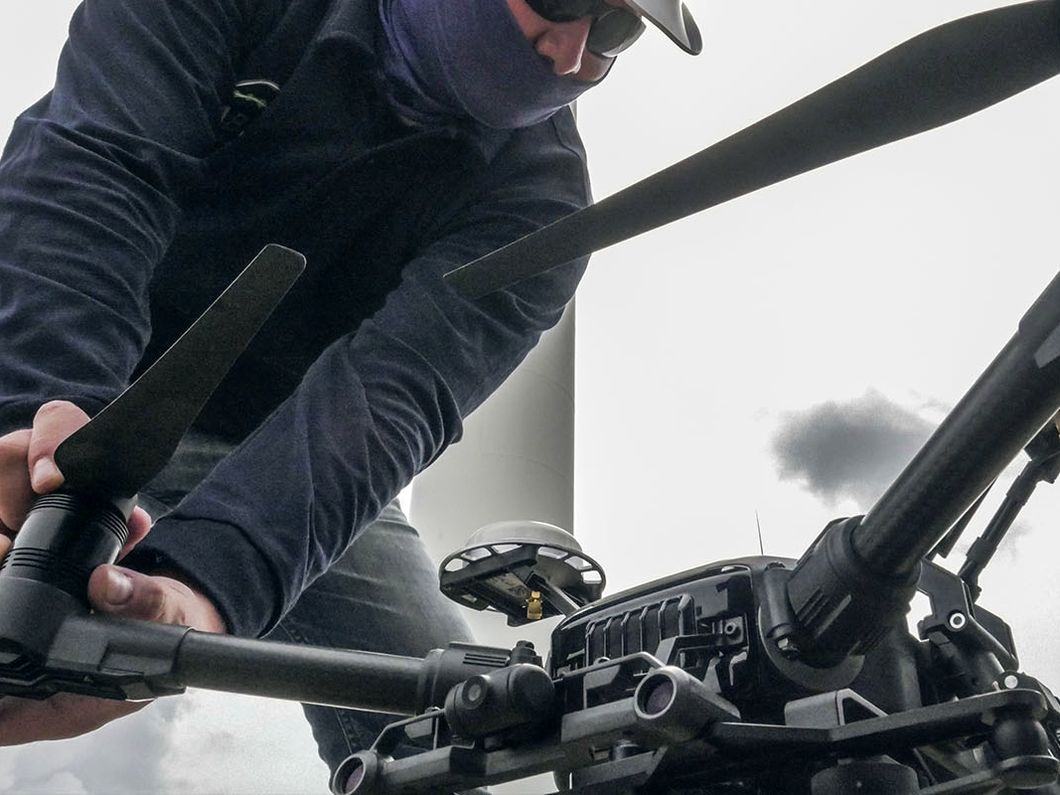 Piloto preparando el dron de inspección junto a un aerogenerador