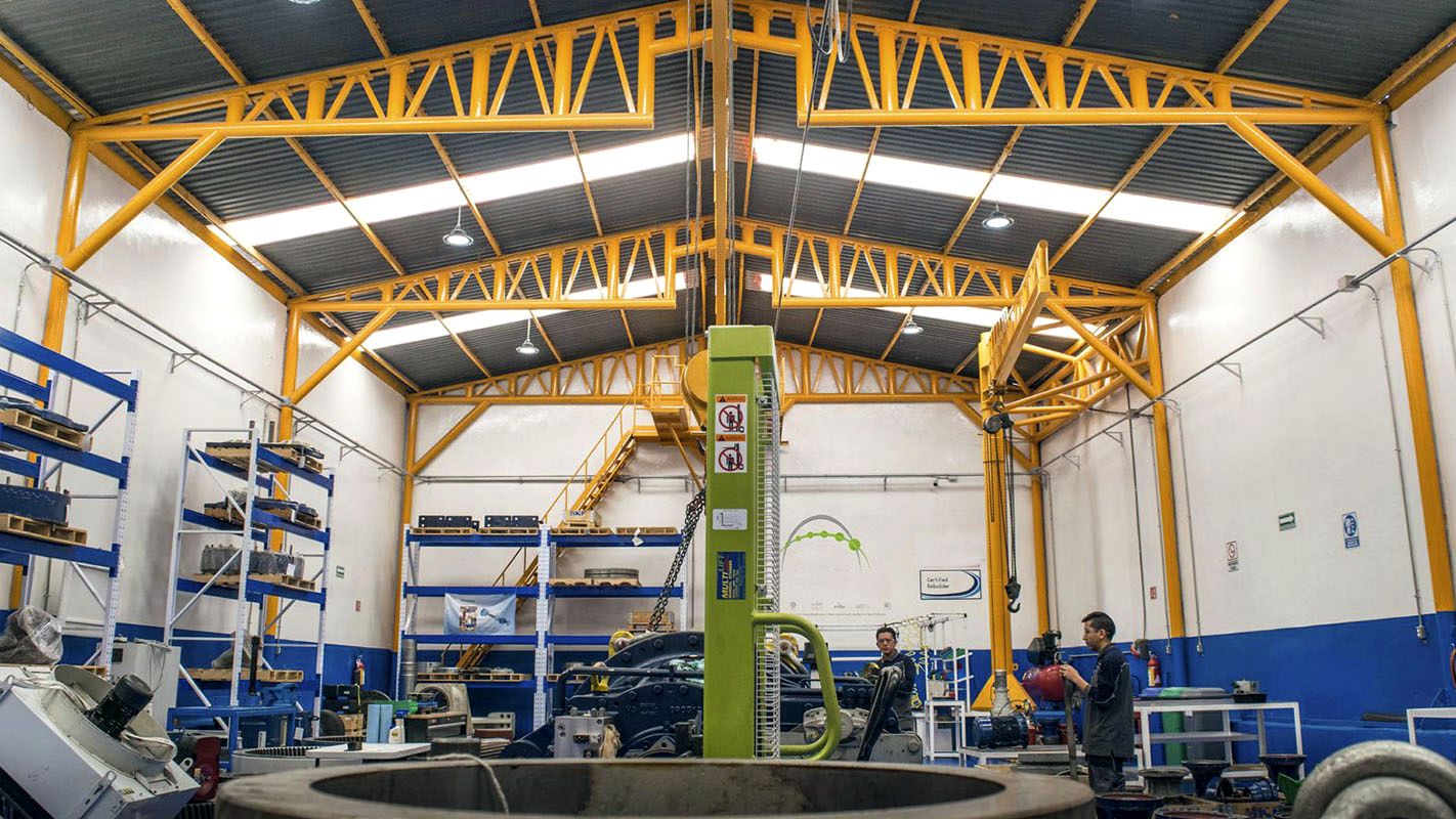 Interior de una nave industrial con estructura amarilla y bancos de trabajo